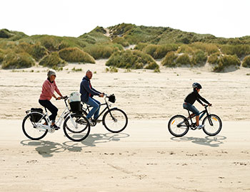 Eine Familie fährt am Strand von Blokhus mit dem Fahrrad