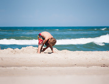 Ein kleiner Junge gräbt auf dem Strand von Tornby